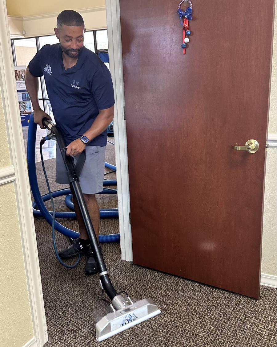 Richard Johnson, owner of Elite Carpet, Tile and Grout Cleaning, cleaning an office carpet with an extraction wand