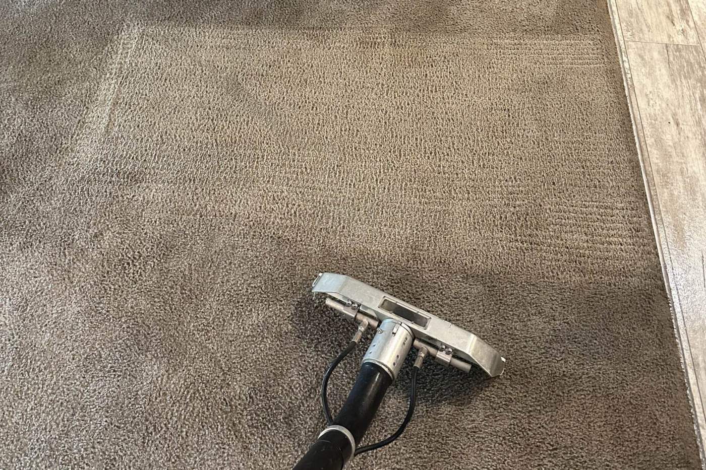 Carpet extraction wand on a hallway traffic lane Carpet extraction wand partway down a soiled hallway carpet, with the freshly cleaned stripe lighter than the carpet around it